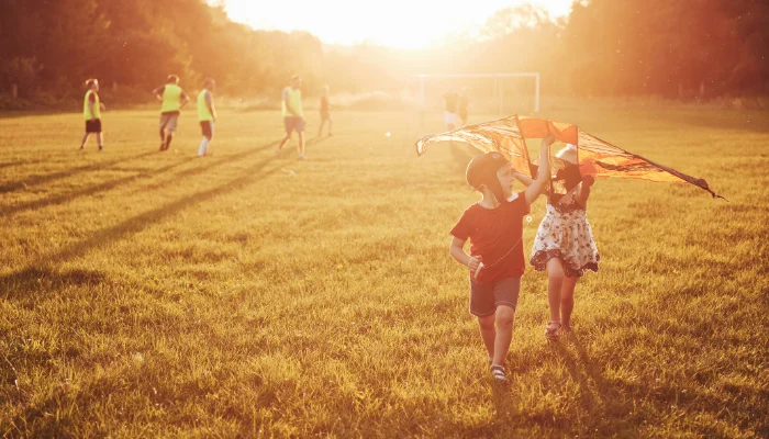 Kids flying kite in sunset field